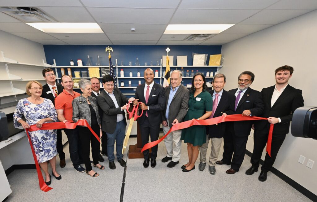 Governor Wes Moore, Liatris leadership, State and Local elected officials stand behind a ribbon and with ceremonial scissors in a scientific lab