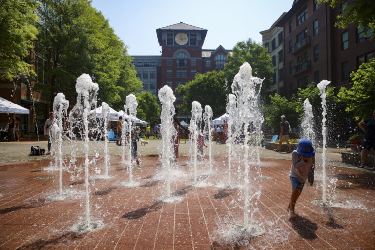Water fountains in the foreground of Rockville Town Center Park with a clock tower in the background